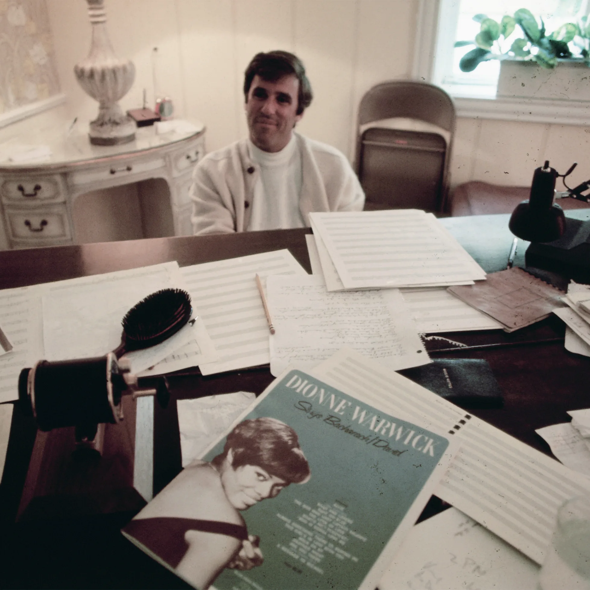 Burt Bacharach working in his home office with music sheets and Dionne Warwick record.