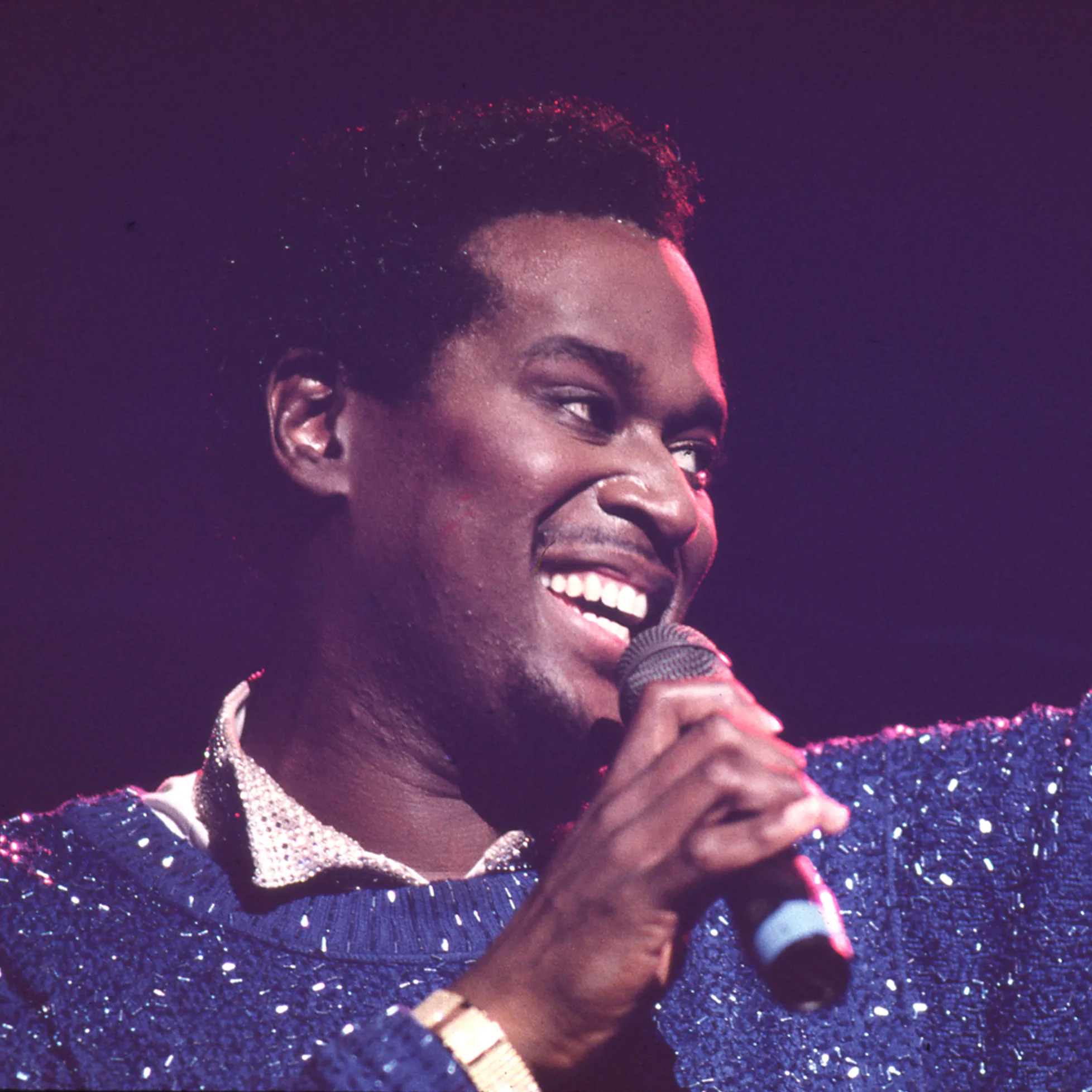 Luther Vandross singing into a microphone on stage.