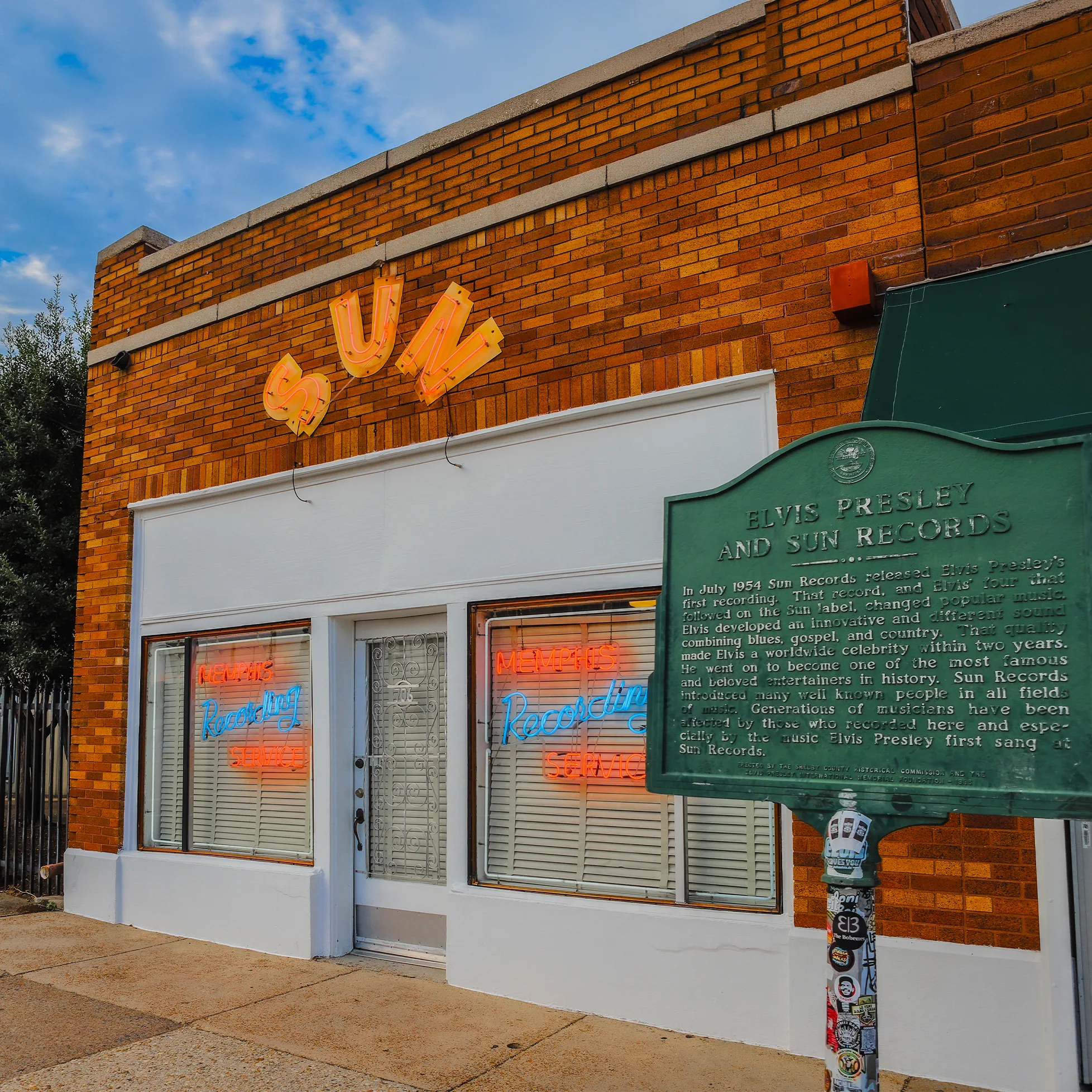 Sun Records studio building in Memphis with iconic neon signs and Elvis Presley historical marker.