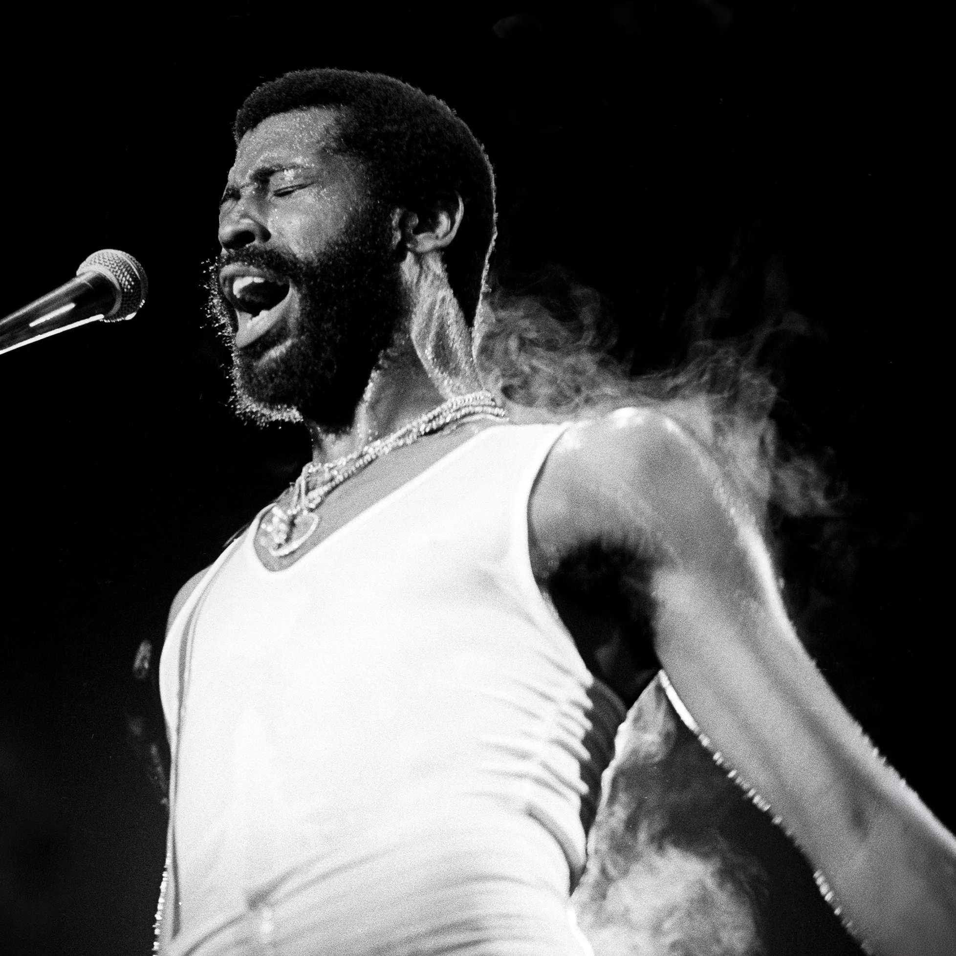 Teddy Pendergrass performing live on stage, singing passionately into the microphone.
