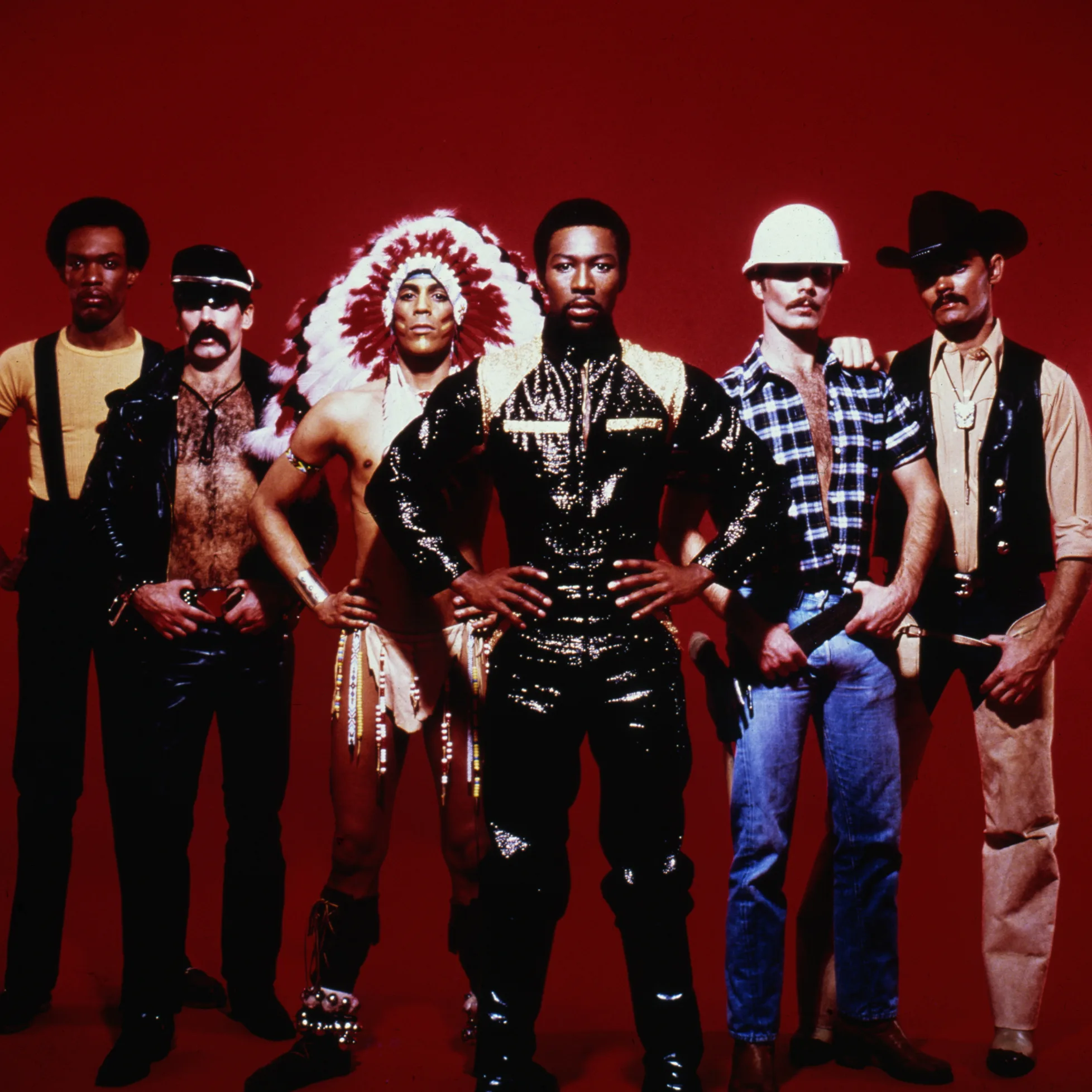 Village People in their iconic costumes posing against a red background.