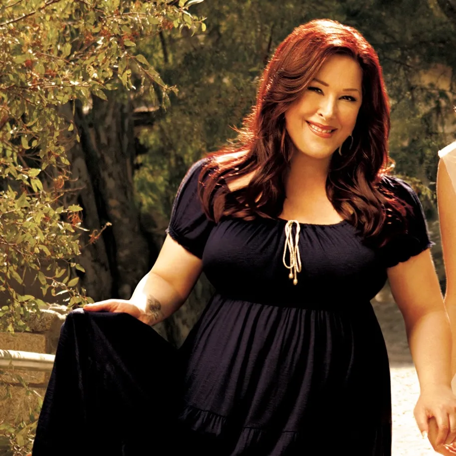 Photo of Carnie Wilson wearing a black dress, standing in a wooded area.