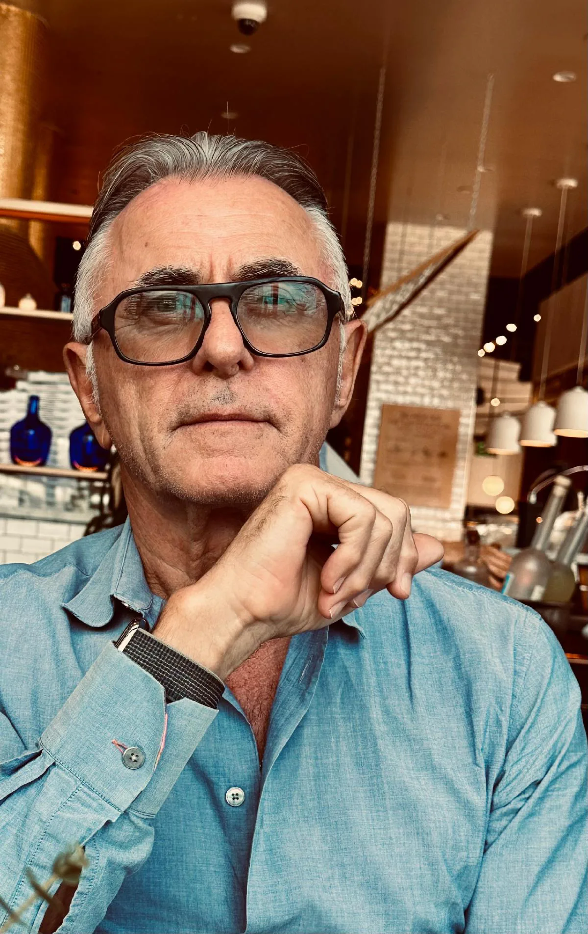 Kieth Forsey seated in a cafe, wearing sunglasses.