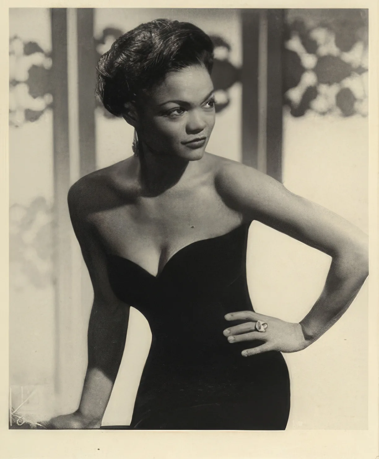 Portrait of Eartha Kitt in a black dress with her hand on her hip.
